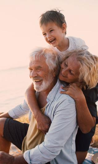 Couple de grands-parents souriants avec leur petit fils à la plage