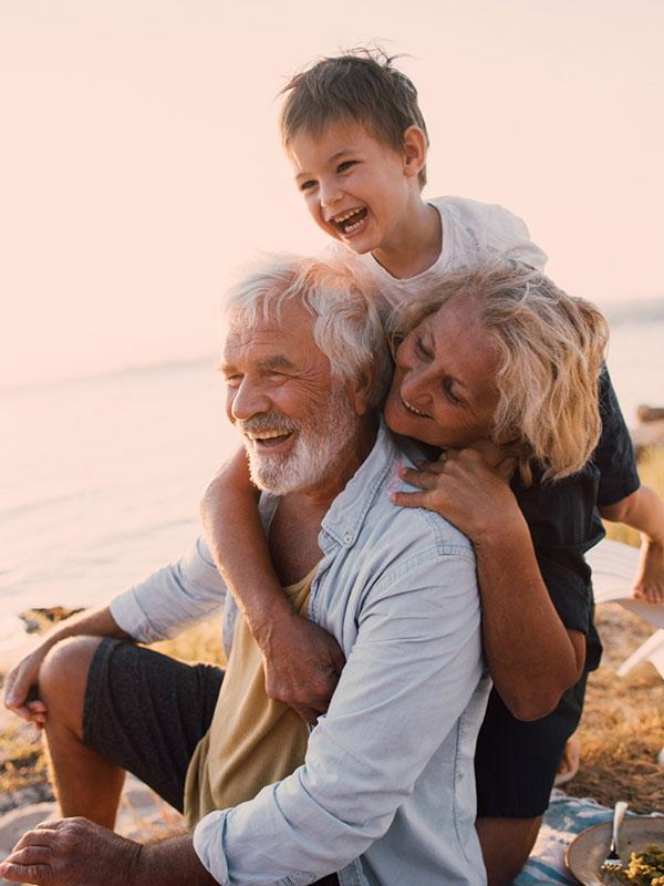 Couple de grands-parents souriants avec leur petit fils à la plage