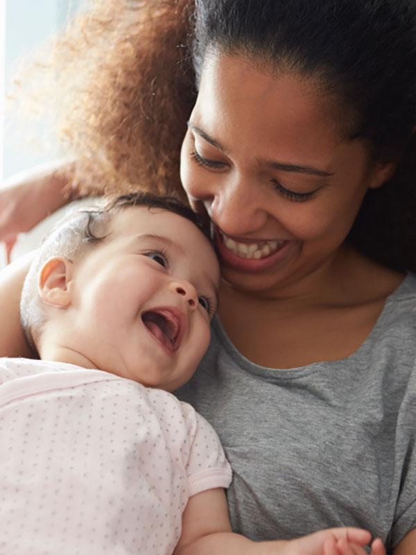 Mamá con un bebé en brazos y sonriéndose