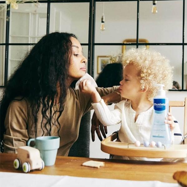 Une petite fille essuye le visage de sa maman avec un produit Mustela