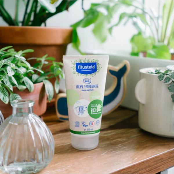 Tube of Mustela certified Organic on a shelf with plants 