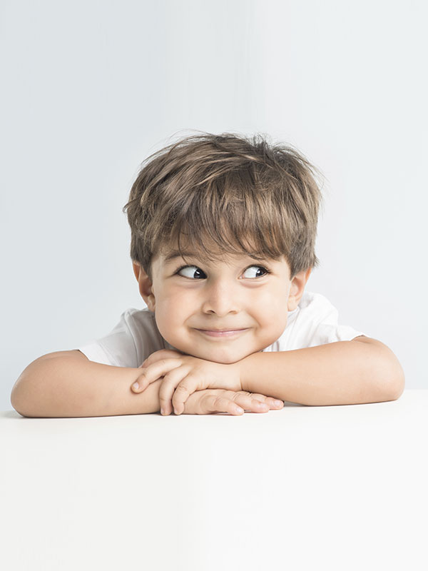 Enfant allongé sur le ventre avec la tête posée sur ses bras croisés et qui regarde vers la droite